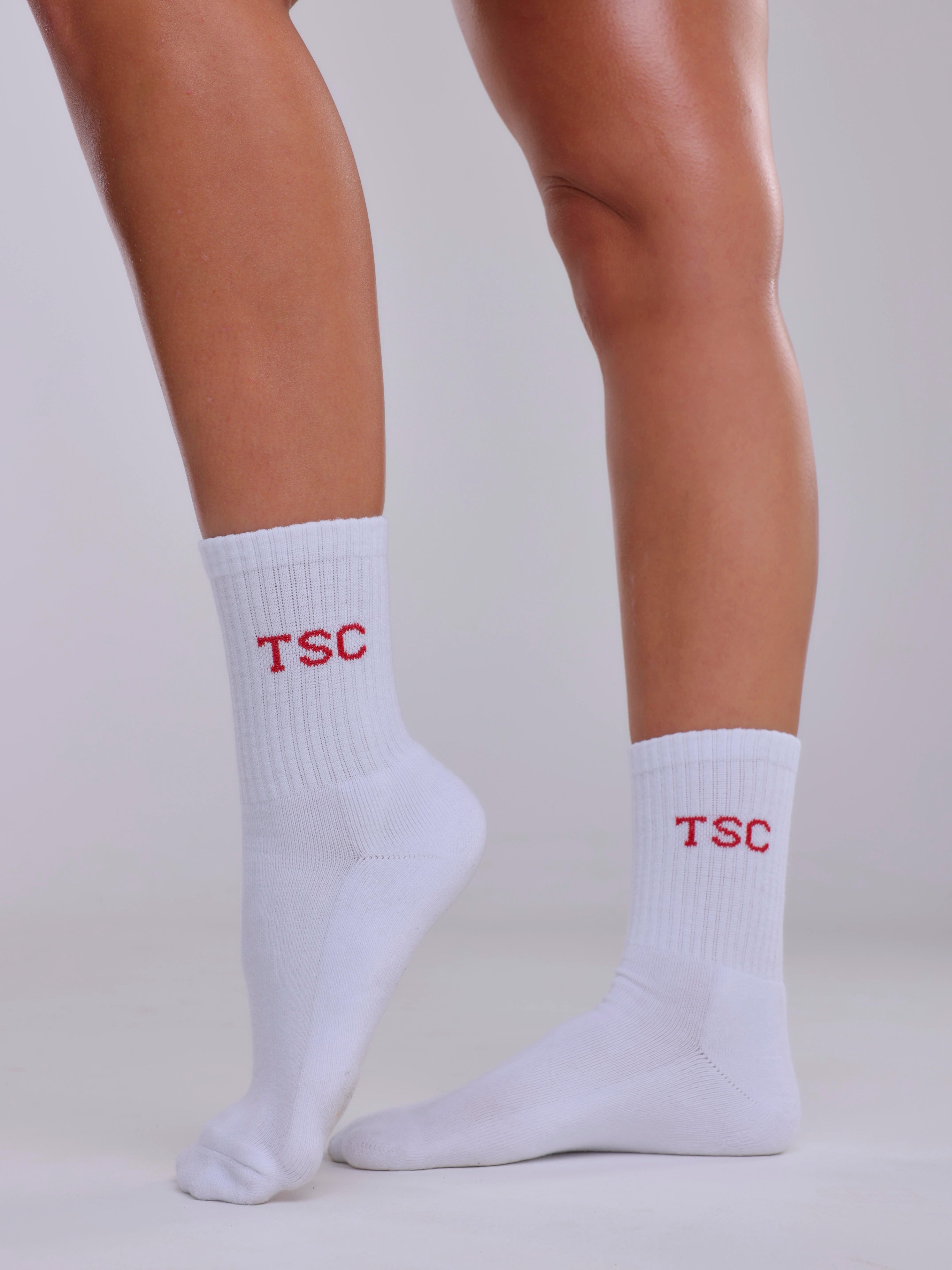 White socks with 'TSC' logo worn by a person on a light gray background